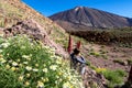 Tourist woman sitting in field of red flowers Tajinaste. Scenic view on volcano Pico del Teide, Mount El Teide National Park Royalty Free Stock Photo