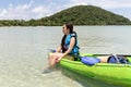 Tourist woman sitting on kayak lookign at beautiful tropical beach on vacation.