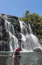 Tourist woman sitting near the huge beautiful waterfall
