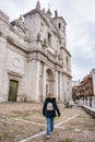 Tourist woman strolling past the imposing medieval cathedral in Valladolid, Spain.