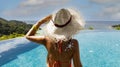 Back view  tourist woman Suntan lotion applying sunscreen solar cream on the poolside and looking view with seashore Royalty Free Stock Photo