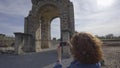 Tourist woman taking a picture with camera of the Arch of Caparra, ancient roman city of Caparra in Extremadura, Spain