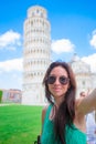Tourist woman taking selfie background famous Pisa Tower. Woman traveling visiting The Leaning Tower of Pisa. Royalty Free Stock Photo