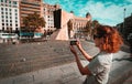 Tourist woman taking a picture with the smartphone in Plaza de Catalunya, Barcelona.