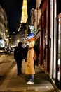 Woman in trench coat with backpack walking in night Paris