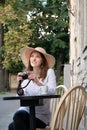 Tourist woman digital camera street cafe terrace girl hat sun vintage travel photo shooting white cup coffee panasonic lumix Royalty Free Stock Photo