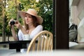 Tourist woman digital camera street cafe terrace girl hat sun vintage travel photo shooting white cup coffee panasonic lumix Royalty Free Stock Photo