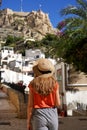 Tourist woman walking in the neighborhood Santa Cruz looking at Mount Benacantil with Santa Barbara castle in Alicante, Spain