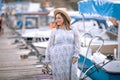 Tourist woman walks on wooden moor pier with touristic yachts