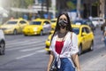 A tourist woman wearing a cloth face mask walks on the busy streets of Athens