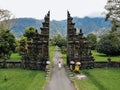 Tourist woman in white dress walking through Traditional Balinese Hindu gate Candi Bentar close to Bedugul, Bratan lake