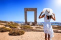 A tourist woman in a white dress looks at the famous marble gate of Naxos