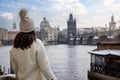 A tourist woman enjoys the view of the snow covered skyline of Prague