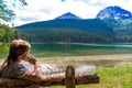 Tourist woman on a wooden bench near Glacial Black Lake. Durmitor National Park. Montenegro