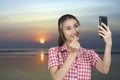 Tourist women takes selfie while sunset by the beach Royalty Free Stock Photo