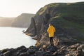 Tourist in yellow jacket looks at cliffs near Sorvagsvatn lake Royalty Free Stock Photo