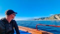 Touristic man on boat with panoramic view from open sea on snow capped volcano Mount Etna in Taormina, Sicily, Italy, Europe, EU.