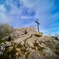 Tourists admire the Alpspitze mountains in Werdenfelser Land next to a simple wooden puritanical cross