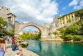 Tourists aim cameras as a Bosnian diver prepares to jump into the Neretva River in Mostar, Bosnia