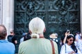 Tourists appreciating the beautiful bas-reliefs on the bronze door of  building of the Milan Cathedral Duomo di Milano, the Royalty Free Stock Photo