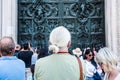 Tourists appreciating the beautiful bas-reliefs on the bronze door of building of the Milan Cathedral Duomo di Milano, the