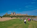 Tourists approach the ruins of the 14th-century Dunstanburgh Castle on the Northumberland coast in the north east UK Royalty Free Stock Photo