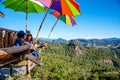 Tourists asian couple sitting eat noodle on the wooden platform and looking scenic view of beautiful nature mountains at Ban Jabo,