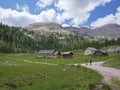 Tourists with Backpacks about to Take a Dirt Route on a Road in the Italian Alps Mountains on a Summer day, Italy