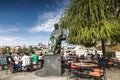 Tourists in cafes on the banks of the Vltava river near the monument to famous czech composer Bedrich Smetana infront of The Bedri