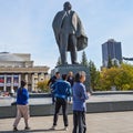 Tourists from China taking pictures at the background of the sculpture of Lenin and the Novosibirsk state academic Opera and ball