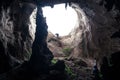 Tourists climbing up large hole on ceiling of rocky cave