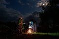 Tourists cook food in a cauldron on fire. Two men are cooking food in a cauldron on a tourist campfire at night and chatting