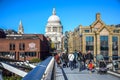 Tourists crossing the River Thames by walking through Millennium Bridge with Saint Paul`s Cathedral in background, London, UK Royalty Free Stock Photo