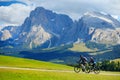 Tourists cycling in Seiser Alm, the largest high altitude Alpine meadow in Europe, stunning rocky mountains on the background Royalty Free Stock Photo