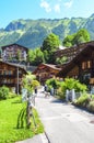 Tourists with dog walking in picturesque Alpine village Wengen in Switzerland in summer season. Mountain chalets surrounded by Royalty Free Stock Photo