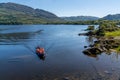 Tourists enjoy a boat ride on Muckross Lake in Killarney National Park on a beautiful summer day