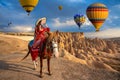 Tourists enjoy ride horses and looking to balloons in Cappadocia, Turkey