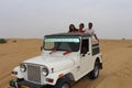 Tourists enjoying adventurous open jeep safari in Jaisalmer desert camp Royalty Free Stock Photo