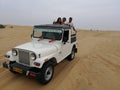 Tourists enjoying adventurous open jeep safari in Jaisalmer desert camp Royalty Free Stock Photo