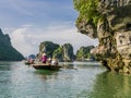 Tourists enjoying a boat trip with local guides through the majestic limestone mountains of Halong bay, Vietnam Royalty Free Stock Photo