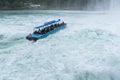 Tourists enjoying boat trip in Rheinfall waterfall in Switzerland