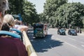 Tourists enjoying city views from top deck of of tour bus in London, UK, on a bright summer day Royalty Free Stock Photo