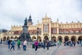 Tourists at Krakow`s Main Square with Cloth Hall and Adam Mickiewicz Monument, Poland