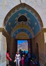 Tourists entering arch gate with colorful paintings at Panormitis Monastery.
