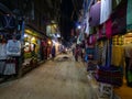 Tourists explore the shops while walking along the unpaved street in Kathmandu.