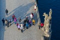 Tourists are on famous medieval Charles Bridge near sculptural composition Madonna and St. Bernard, aerial view, Prague