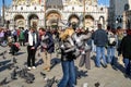Tourists feed pigeons in the main square of Venice San Marco