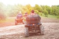 Tourists on a few quad bikes ride on rough terrain on a sunny day in the spring. Toned photo