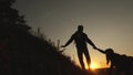 Tourists go down from the goy in the sunset, holding hands. male traveler holds the hand of a female traveler going down