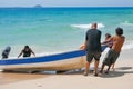 Tourists help Malaysian man to get his boat to the beach Royalty Free Stock Photo